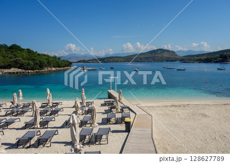 beach umbrellas closed during low season on the beach in Ksamil, Albanian rivieira 128627789