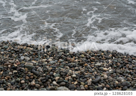 Foam from a receding wave on a stone beach in Batumi, 128628103