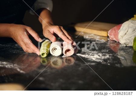 Hands Preparing Homemade Pasta with Tri-Colored Dough Representing Italian Cuisine 128628187