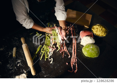 Chef Preparing Colorful Italian Pasta with Fresh Dough on a Floured Countertop 128628286