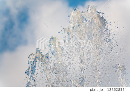 Splashes and jets of water against light background. Splashes and jets of water against light background. 128628554
