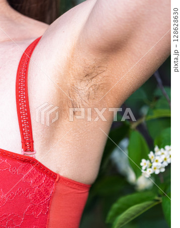 Closeup of long dark hair growing under arm of young female. Concept of hygiene, natural beauty, feminity and body hair growth 128628630