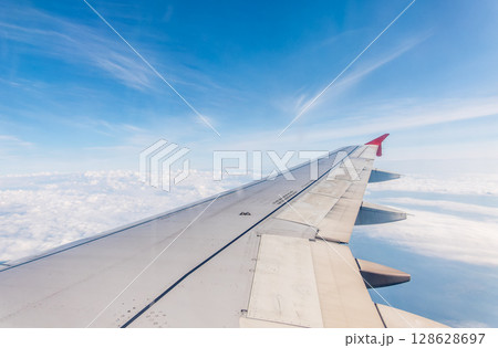 View from the airplane window at a beautiful cloudy sky and the airplane wing View from the airplane window at a beautiful cloudy sky and the airplane wing 128628697