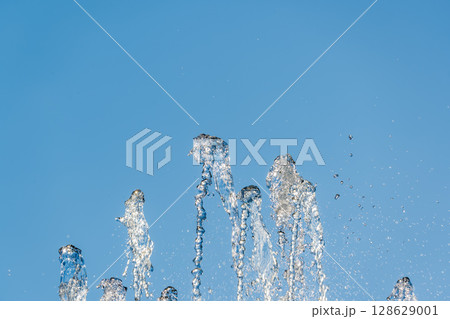 Splashes and jets of water against light background. Splashes and jets of water against light background. 128629001