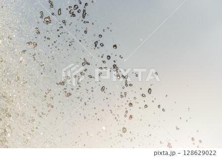 Splashes and jets of water against light background. 128629022