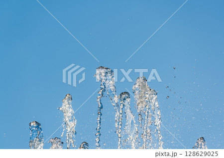 Splashes and jets of water against light background. Splashes and jets of water against light background. 128629025