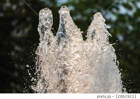 Splashes of water on dark background. Water sprays in sunny day close-up. 128629211