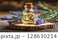 Aromatic Elixir: Essential oil in a glass bottle with cork stopper, nestled among sprigs of purple flowers on a wooden base, capturing the essence of nature. 128630214