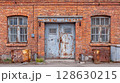 Weathered brick building with rusted metal doors and windows, showcasing age and decay. Urban decay, architecture, texture, and grunge aesthetic. 128630215