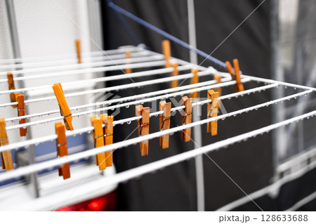 Wooden clothespins on outdoor drying rack with droplets Wooden clothespins on outdoor drying rack with droplets 128633688