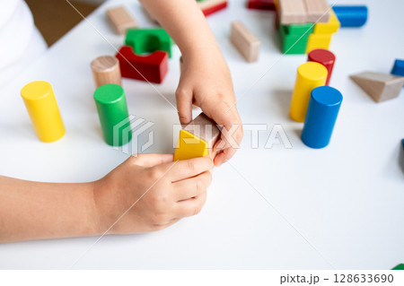 Child playing with colorful wooden blocks on white table 128633690