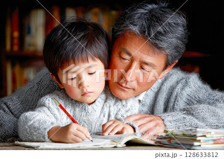 Grandfather and grandson engaged in learning together at a cozy indoor setting 128633812