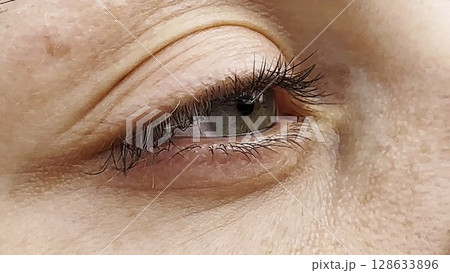 Focus on right green eye of attractive girl blinking and looking into camera. Portrait of upset female face. Sorrowful facial expression of young woman. Unhappy sight of beautiful lady. Close up 128633896