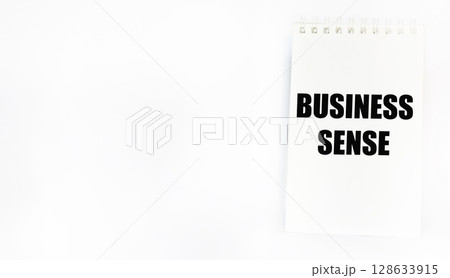 A symbol of business sense. Conceptual words business sense on a notebook. White background, 128633915