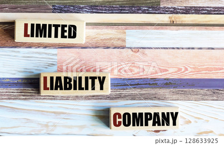 LLC is the text of a limited liability company on wooden blocks on a beautiful background.  LLC is the text of a limited liability company on wooden blocks on a beautiful background.  128633925