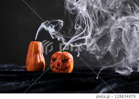 Halloween-style candles on a dark background. Festive decor. 128634879