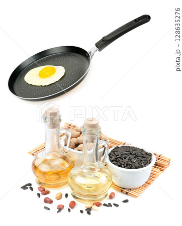 Fried eggs in a frying pan and a set of vegetable oils for frying isolated on white background. 128635276
