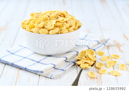 corn flakes in a ceramic bowl on a white wooden table, selective focus. corn flakes in a ceramic bowl on a white wooden table, selective focus. 128635992
