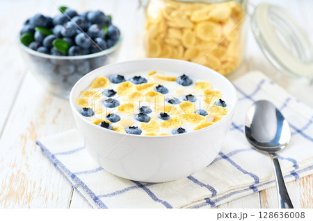 breakfast with corn flakes and blueberry on a white wooden table, selective focus. breakfast with corn flakes and blueberry on a white wooden table, selective focus. 128636008