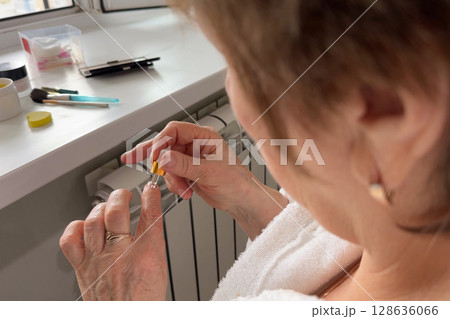 Senior woman hands holding bottle of cuticle oil Senior woman hands holding bottle of cuticle oil 128636066
