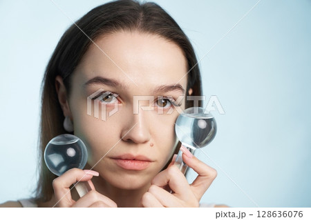Woman using magnifying glasses for skin analysis in a studio setting 128636076