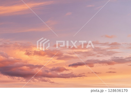 Warm golden hour sky with pastel orange and pink clouds, perfect for dreamy nature themes and sunset background designs 128636170