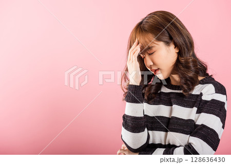 Portrait of beautiful Asian young woman sad tired strain face holding hold head by hands, female person closed eyes problem she headache, studio shot isolated on pink background Portrait of beautiful Asian young woman sad tired strain face holding hold head by hands, female person closed eyes problem she headache, studio shot isolated on pink background 128636430