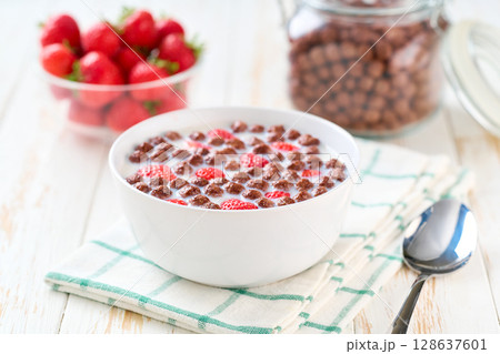 Healthy breakfast for kids with chocolate corn balls and strawberry on a light kitchen table, selective focus. Morning breakfast. 128637601