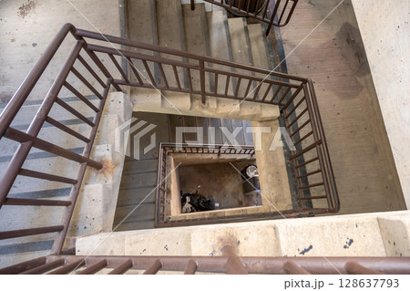 Looking down the center of a twisting stairwell in a parking ramp with trash and dirt Looking down the center of a twisting stairwell in a parking ramp with trash and dirt 128637793