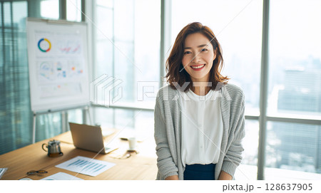 20代後半女性アナリストが笑顔でデータ共有する会議室風景 128637905