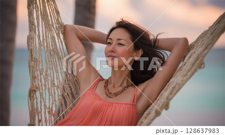 中年の日本人女性が砂浜で夕景を眺める 128637983