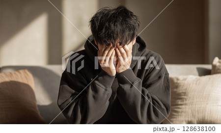 十代の日本人の少年がソファの上で目を覆う 128638100