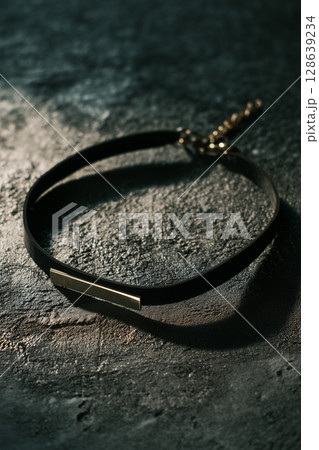レザーブレスレットと暗めのテクスチャ背景｜高級感あるアクセサリーイメージ 128639234