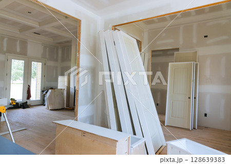 Stacked white doors unfinished walls indicate ongoing renovation work in an expansive home interior. 128639383