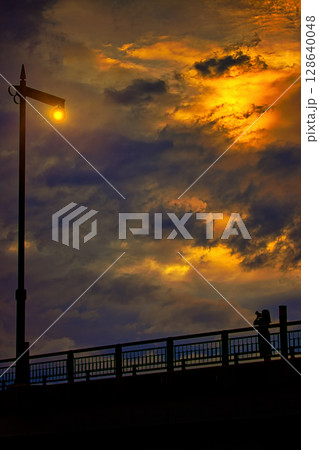 橋の上に立つ街灯を撮る女性 128640048