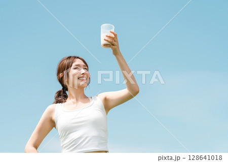 運動時にプロテイン・EAA・ドリンクを飲む女性(青空) 運動時にプロテイン・EAA・ドリンクを飲む女性(青空) 128641018
