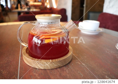 A beautifully crafted teapot with herbal tea and citrus fruits rests on a rustic table 128641674