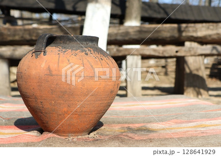 A Rustic Clay Pot Beautifully Displayed on a Wooden Table, Surrounded by a Charming Atmosphere 128641929
