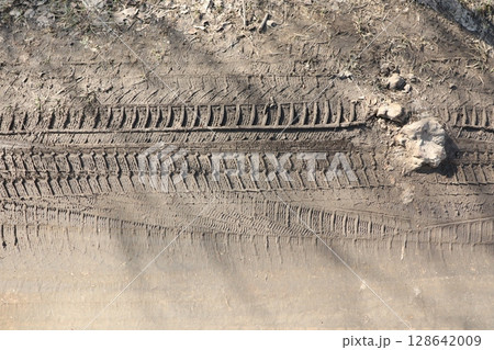 Tire Tracks Present on a Dirt Surface Illuminated by Natural Light During the Daytime Tire Tracks Present on a Dirt Surface Illuminated by Natural Light During the Daytime 128642009