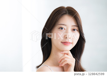 美しい若い女性の素肌感が美しい顎に手を当てて考えるポーズ　美容やビューティーイメージカメラ目線	 128642599