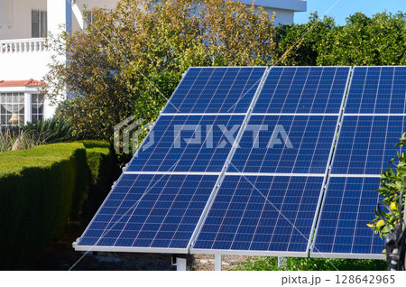 Solar panels gleaming under the sun at a residential garden in a vibrant neighborhood. 128642965