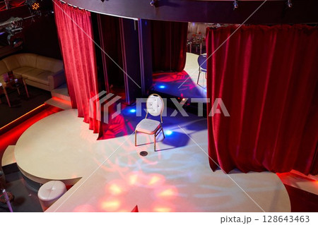 A vibrant stage with luxurious red curtains and a brilliant spotlight for captivating shows A vibrant stage with luxurious red curtains and a brilliant spotlight for captivating shows 128643463