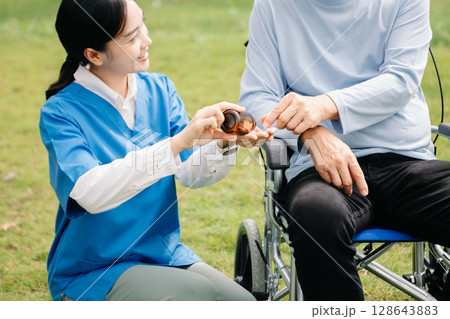 Elderly asian senior woman on wheelchair with Asian careful caregiver and encourage patient, walking in garden. with care from a caregiver Elderly asian senior woman on wheelchair with Asian careful caregiver and encourage patient, walking in garden. with care from a caregiver 128643883