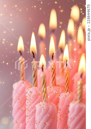 A close-up image of festive pink birthday candles with flickering flames and a dreamy, sparkly background. 128644670