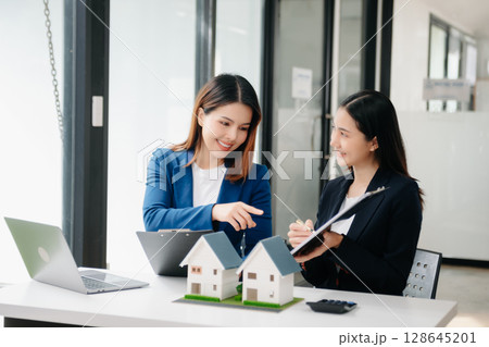 Real estate broker agent presenting and consult to customer to decision making sign insurance form agreement, home model, concerning mortgage loan offer Real estate broker agent presenting and consult to customer to decision making sign insurance form agreement, home model, concerning mortgage loan offer 128645201