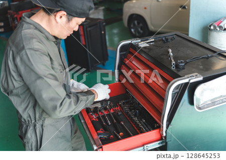 整備工場で働く整備士・自動車整備士・メカニックの中年アジア人男性 整備工場で働く整備士・自動車整備士・メカニックの中年アジア人男性 128645253