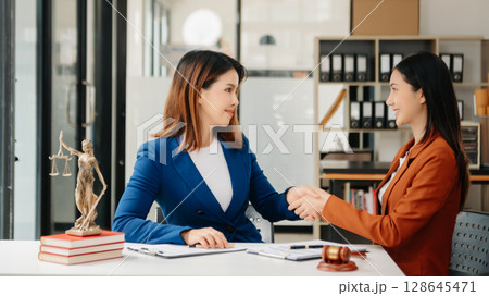 Asian Business and lawyers discussing contract papers with brass scale on desk in office. Law, legal services, advice, justice and law concept . Asian Business and lawyers discussing contract papers with brass scale on desk in office. Law, legal services, advice, justice and law concept . 128645471