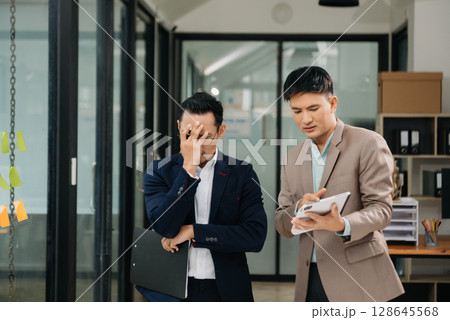 Furious two Asian businesspeople arguing strongly after making a mistake at work in modern office Furious two Asian businesspeople arguing strongly after making a mistake at work in modern office 128645568