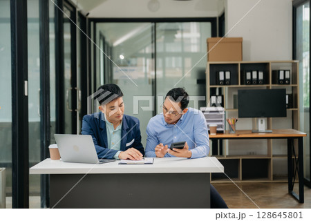 Male discussing new project with business colleague. Young man talking with young man in office. Male discussing new project with business colleague. Young man talking with young man in office. 128645801