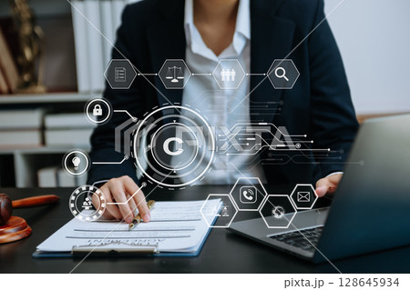 Copyright or patent concept, Person hand using laptop computer, tablet and smartphone with virtual screen copyright icon trademark, Creation ownership against piracy. at office 128645934